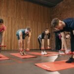 Dorośli ćwiczący z hantlami na grupowych zajęciach fitness w sali
