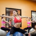 Kobiety na zajęciach fitness rozciągają się na piłkach w klubie