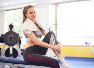 Jak polubić cardio, siłownię i stretching, jeśli do tej pory kojarzyły Ci się z karą Aktywna kobieta siedzi na siłowni z ręcznikiem na szyi