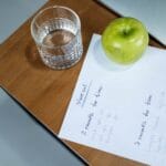 Jabłko, woda i plan treningowy na drewnianym biurku